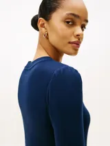 Vestido midi de color azul marino, confeccionado en algodón, con cuello redondo, mangas tres cuartos ligeramente abullonadas y logo de la marca bordado en el pecho.