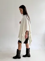 Ruana de tejido de punto trenzado en color crudo, con diseño abierto, corte holgado y mangas amplias tipo kimono.