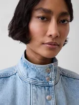 Campera bomber de jean con lavado claro, cuello alto con botones a presión, cierre frontal, bolsillos con solapa en el pecho y elástico en el dobladillo inferior y los puños.
