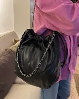 Cartera tipo bolso capitoneada de cuero color negro, con asa de cadena plateada y cuero entrelazado. Forrada por dentro y con bolsillo interno.