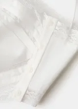 Top asimétrico de lino y viscosa color crudo, con tirantes finos tipo halter, escote diagonal y detalles de encaje en los bordes.