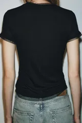 Camiseta de manga corta color marrón oscuro con textura acanalada, cuello redondo y bajo recto. Presenta un bajo superpuesto de tul o tela más clara, visible en el ruedo y en el cuello.