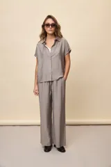 Pantalón gris de corte amplio y silueta fluida, con cintura elástica y cordón ajustable.