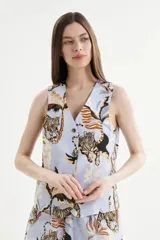 Chaleco celeste con escote en V y cierre frontal con botones. Presenta un estampado de tigres y elementos tropicales.
