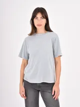 Remera de algodón color gris claro con efecto lavado, cuello redondo y detalle de pequeñas tachas metálicas dispersas en la parte superior delantera y mangas.