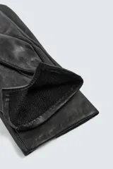 Guantes de cuero negro con interior forrado en tejido de punto. Presentan costuras decorativas en el dorso y tecnología táctil en los dedos para el uso de dispositivos móviles.