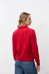 Cardigan de punto color rojo con cuello tipo polo y cierre frontal de botones. Presenta mangas largas con puños acanalados y un corte clásico.