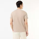 Camiseta de cuello redondo y manga corta color beige, con textura de nido de abeja y pequeña etiqueta decorativa en el borde inferior.