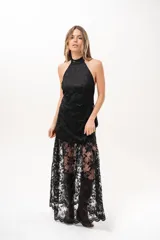Vestido largo negro de encaje con cuello halter y espalda descubierta, con forro corto y falda translúcida.
