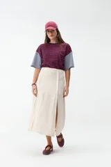 Falda midi de lino color beige, de tiro alto y corte recto, con abertura delantera y cierre cruzado sutil.