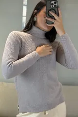 Buzo de punto con cuello alto, diseño de textura acanalada en el frente y mangas largas con puños ajustados.