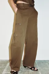 Pantalón de tiro alto con diseño tipo cargo, pernera holgada que se estrecha hacia el tobillo, bolsillos laterales con cierre y bolsillos de plastrón con solapa.