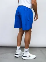 Short deportivo azul con escudo del Club Nacional de Football en la pierna derecha y detalles tricolor.