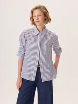 Camisa de corte clásico con estampado de rayas verticales en azul y blanco. Presenta cuello camisero, cierre frontal con botones, bolsillo en el pecho y mangas largas con puños ajustados.