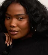 Vestido corto evasé de punto negro con cuello alto y mangas largas.