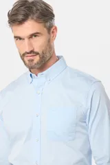 Camisa celeste lisa de corte clásico con cuello abotonado y bolsillo en el pecho.