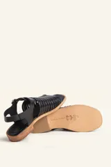 Sandalia plateada de cuero con tiras entretejidas, hebilla lateral y taco bajo.