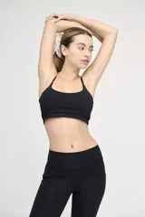 Top deportivo negro con tirantes finos regulables y banda elástica bajo el busto.