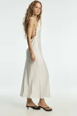 Vestido largo de satén color blanco, con cuello halter y escote en pico, de corte recto y fluido.