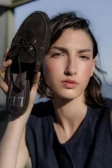 Mocasines tipo náuticos de gamuza color marrón oscuro, con cordones frontales decorativos y suela plana.