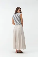 Falda larga beige de corte evasé, con diseño fluido y detalles de costuras verticales en la parte delantera.