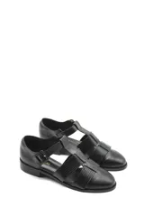 Zapato tipo cangrejera de cuero color marrón, con diseño de tiras entrelazadas, punta cerrada y pulsera con hebilla ajustable al tobillo. Cuenta con un taco bajo de madera.