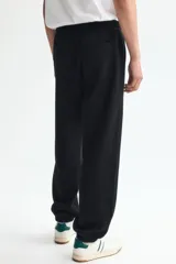 Pantalón deportivo de felpa de mezcla de algodón color negro, con cintura elástica ajustable mediante cordón, bolsillos en las costuras laterales y puños acanalados.