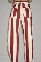 Jeans de tiro alto con corte barrel y diseño de rayas verticales en color bordó y beige. Presenta cierre frontal con cremallera y botón, trabillas en la cintura y bolsillos funcionales en delantero y espalda.