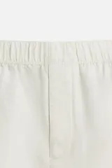 Bermuda relaxed fit confeccionada en tejido ligero de cáñamo. Presenta cintura elástica ajustable con cordón interior, bolsillos laterales y un bolsillo trasero de plastrón con solapa.