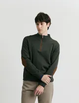 Sweater de punto color verde oliva, con cuello alto y medio cierre frontal. Presenta coderas en símil nappa y puños acanalados.