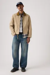 Jeans de corte holgado y tiro medio, con diseño clásico de cinco bolsillos y cierre de botones. Presentan un lavado azul medio con efecto desgastado en los muslos.