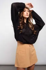 Buzo color crudo de tejido calado con transparencia, de corte holgado y mangas largas.