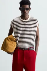 Camiseta sin mangas de punto con cuello redondo, tejido abierto a rayas horizontales negras y blancas, con ribetes en color crema.