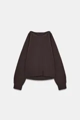 Jersey de punto color marrón oscuro, con cuello redondo y manga larga. Presenta un diseño con aberturas y nudos decorativos en los hombros.