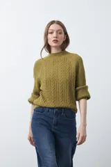 Polera de tejido de punto color verde oliva, con diseño de trenzas frontales y laterales acanalados. Presenta cuello alto, mangas raglán y terminaciones acanaladas en puños y ruedo.