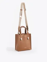 Cartera tipo tote pequeña de cuero color tostado, con doble asa superior y herrajes metálicos plateados en forma de llama en la base de las manijas. Presenta el logo de la marca estampado en la parte inferior frontal.