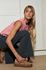 Chaleco de tejido de punto color marrón oscuro, con diseño de ochos y rombos en relieve. Tiene cuello redondo y es sin mangas.