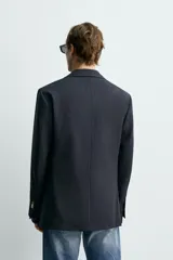Blazer de corte regular confeccionada en lana, con diseño de botonadura cruzada y solapas de pico. Presenta mangas largas, bolsillos de vivo en el pecho y la cadera, un bolsillo interior y una abertura central en la espalda.