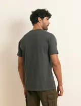 Remera básica de algodón color beige, de manga corta, con cuello redondo y un pequeño detalle bordado en el pecho.