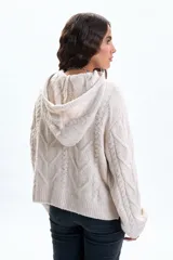 Buzo de punto en color beige con diseño de trenzas, cuello alto con capucha integrada, manga larga y puños acanalados.