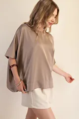 Top de corte oversized con cuello redondo y mangas cortas amplias, confeccionado en tela con acabado satinado.