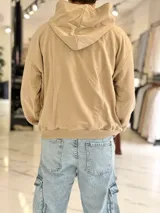 Hoodie de corte boxy fit color gris, con capucha y estampado frontal con la leyenda "Duxon Creative Studios".