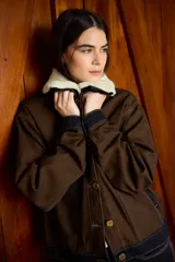Chaqueta de denim color marrón con costuras a la vista, cuello de lana desmontable en color crema y cierre frontal con botones metálicos.