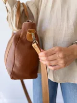 Bolso tipo tote de cuero color marrón con doble asa corta y correa larga extraíble.