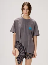 Remera oversize de corte cuadrado, color lila con efecto acid wash, cuello redondo y pequeño gráfico frontal en color rojo.