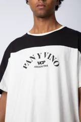 Remera de algodón con diseño color block, combinando tonos beige y verde militar. Presenta cuello redondo y estampa frontal con la frase 'Pan y Vino' y el logo 'VCP Argentina'.