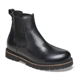Bota tipo Chelsea de cuero negro con paneles elásticos laterales, suela de goma dentada y detalle de costura en el borde de la suela.