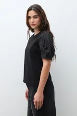 Remera negra de algodón con cuello redondo y mangas cortas abullonadas con detalle de frunces.