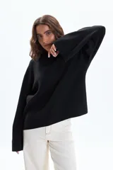 Buzo de tejido de punto color negro, con cuello redondo ajustado y mangas anchas.