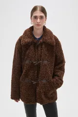 Campera de textura tipo corderito en color marrón, con cuello solapa y cierre frontal mediante tres botones tipo duffle con presillas de cuero sintético.